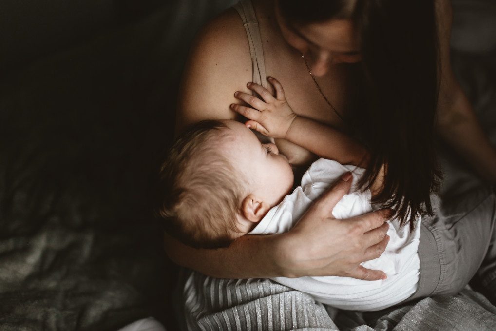 Mother breastfeeding baby with a cold